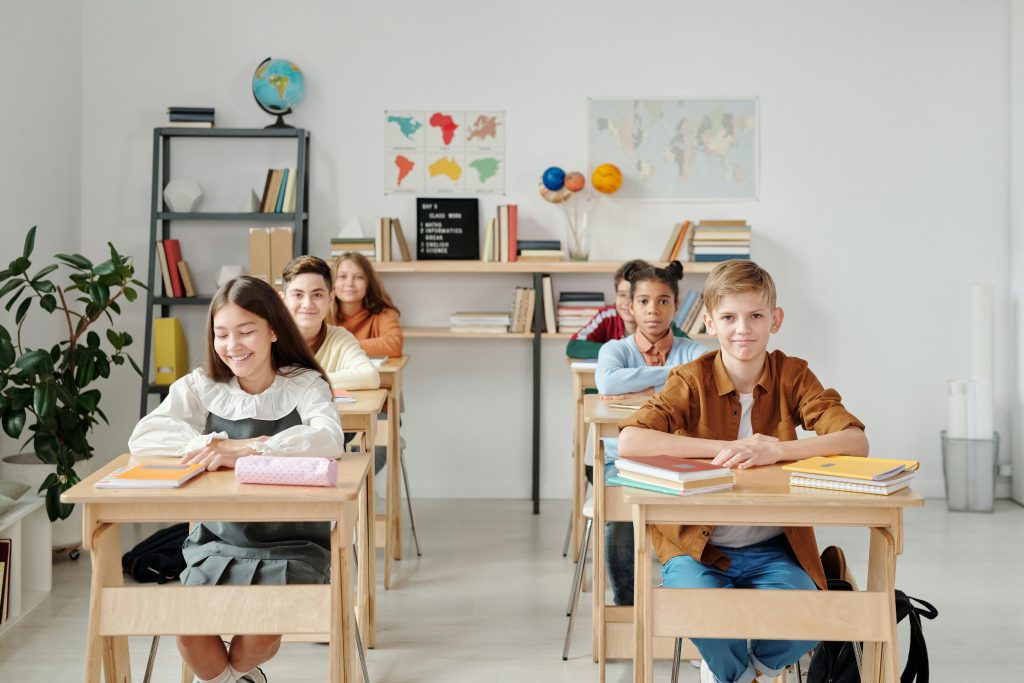 A group of happy students sitting at desks in a modern classroom environment.