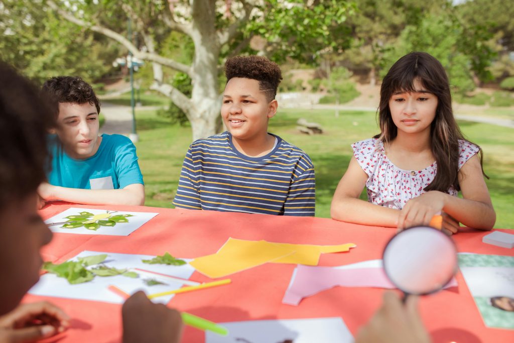 Children engaged in arts and crafts at a summer camp, enjoying outdoor creativity.