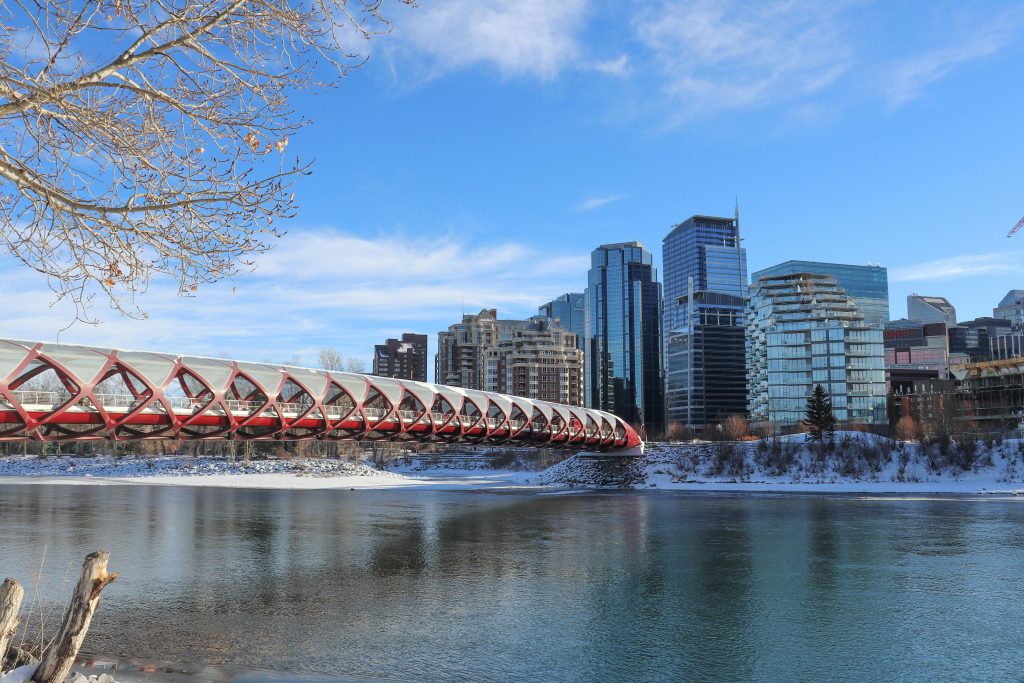 A winter scene of the Peace Bridge over Bow River with Calgary skyline.